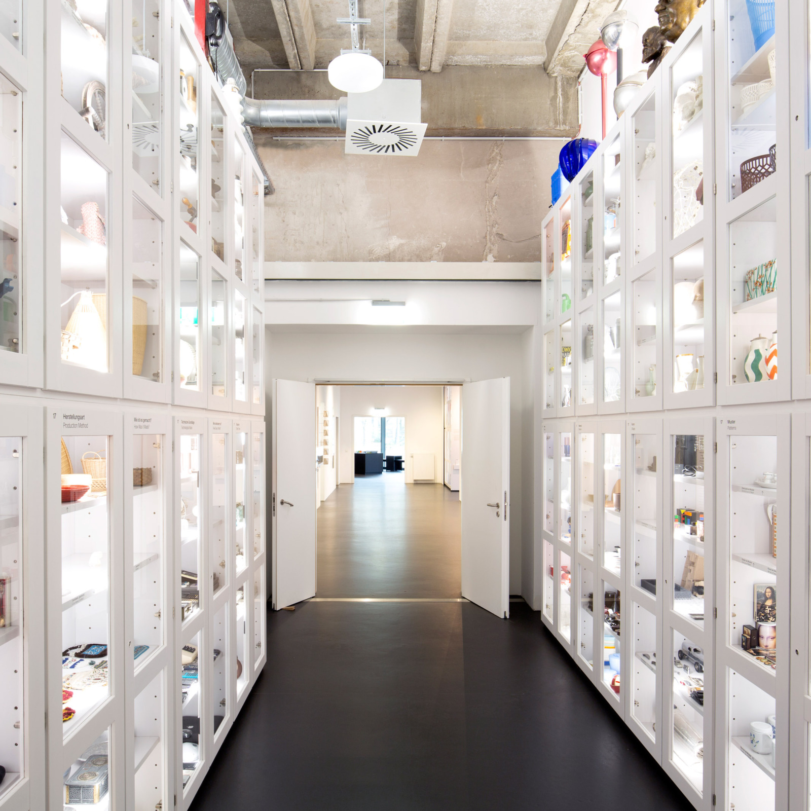 Mit Objekten gefüllte weiße hohe Schränke, auf linker und rechter Seite.