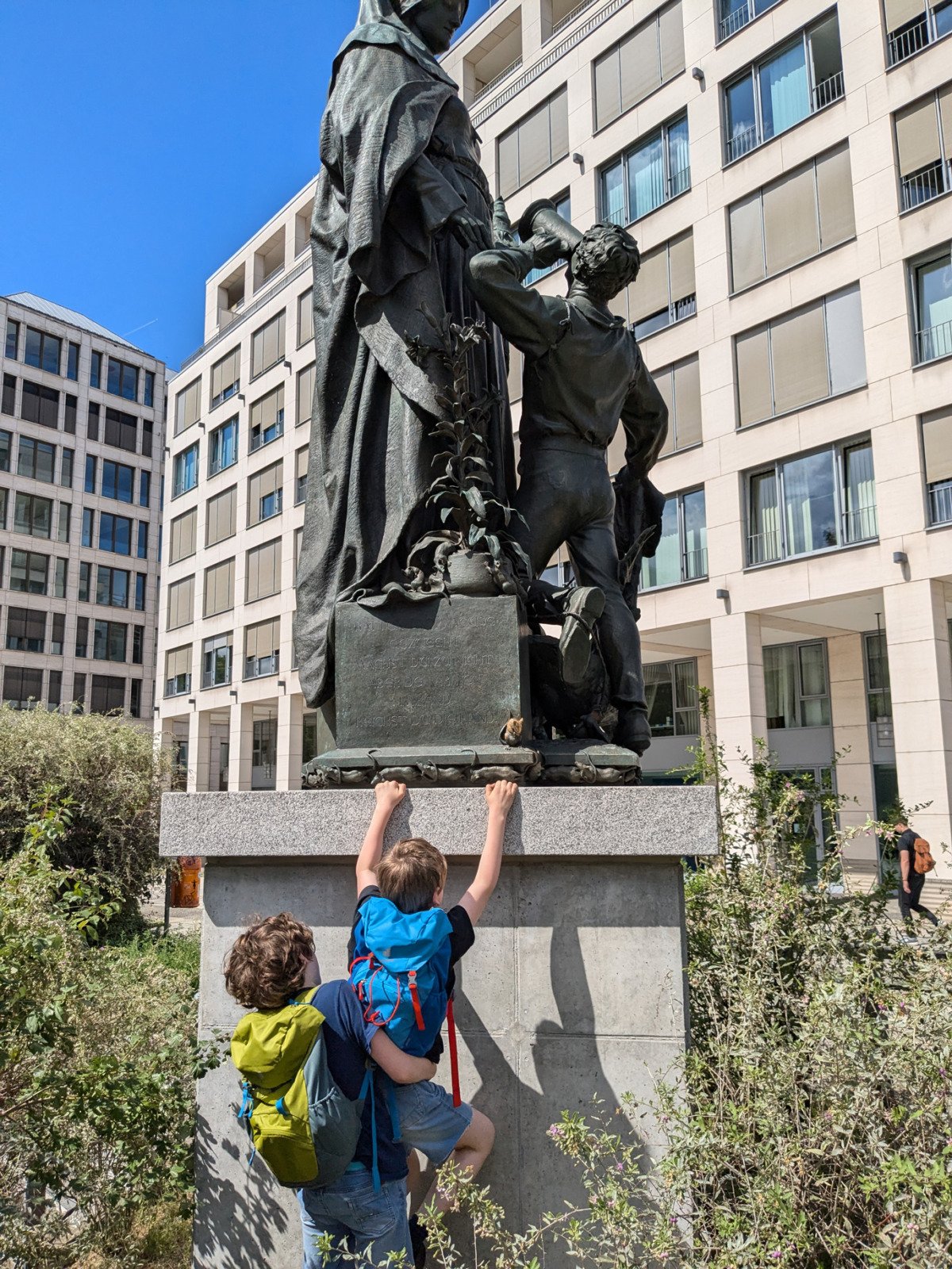 Kinder klettern auf eine Statue im Stadtraum