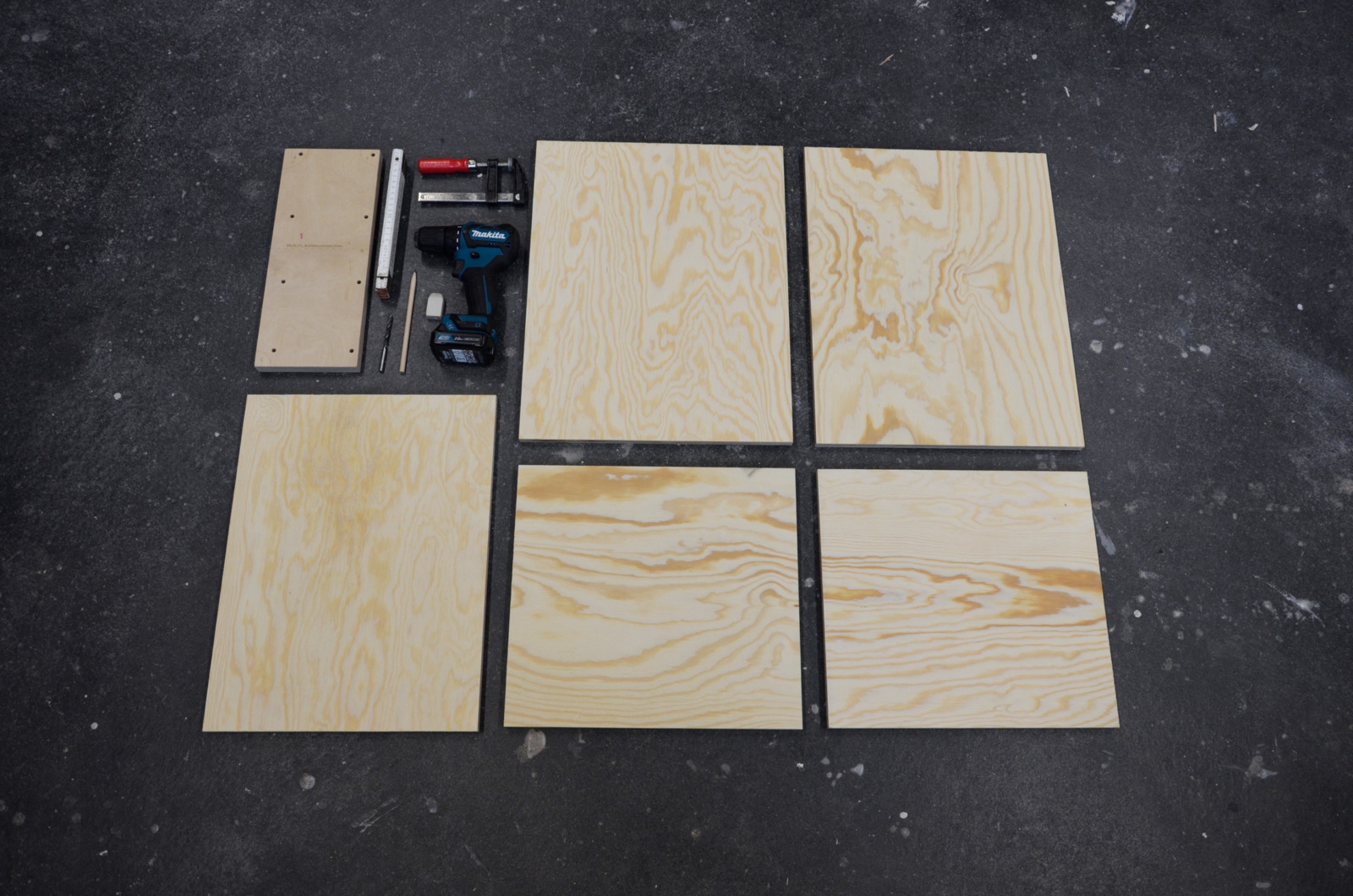 Mehrere dünne Holzplatten liegen neben Werkzeugen auf einem schwarzen Hintergrund