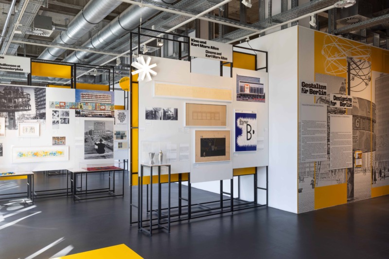 Ausstellungsansicht mit Fotografien, Grafiken, Plakaten und Texttafeln auf weißen Stellwänden in einem modernen Museumsraum