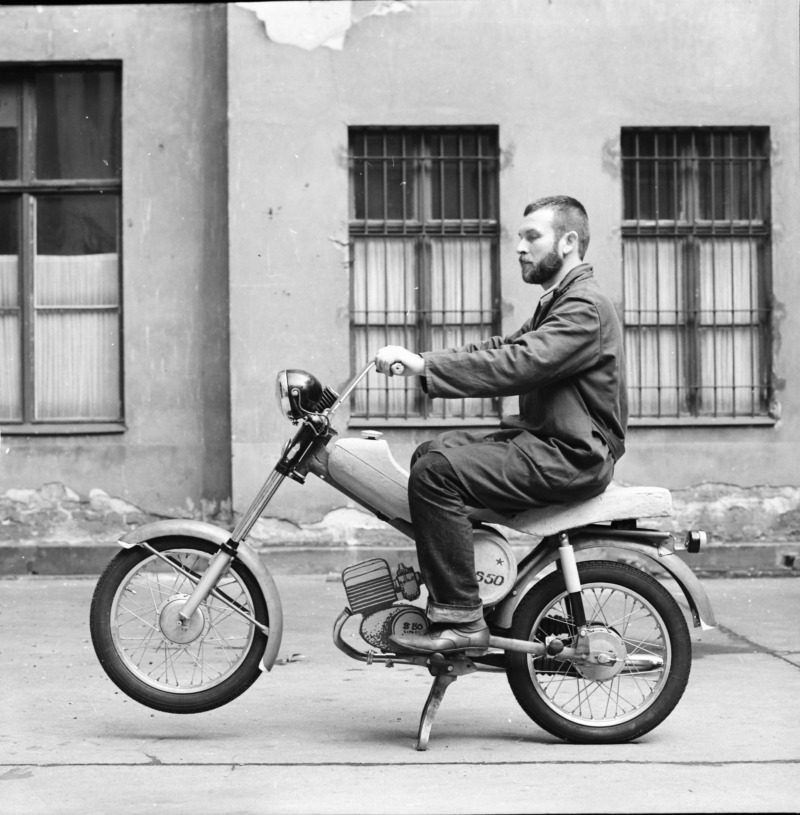 Fotografie eines Mannes, sitzend auf einem Motorradmodell in einem Berliner Hinterhof